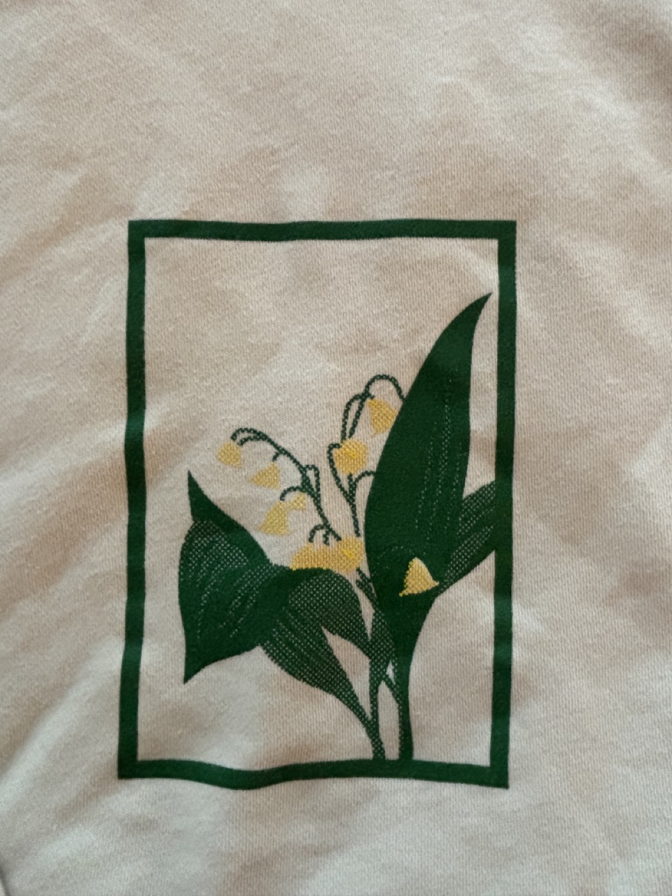 Closer look photograph of the 2 color screen printed design on a beige hoodie.